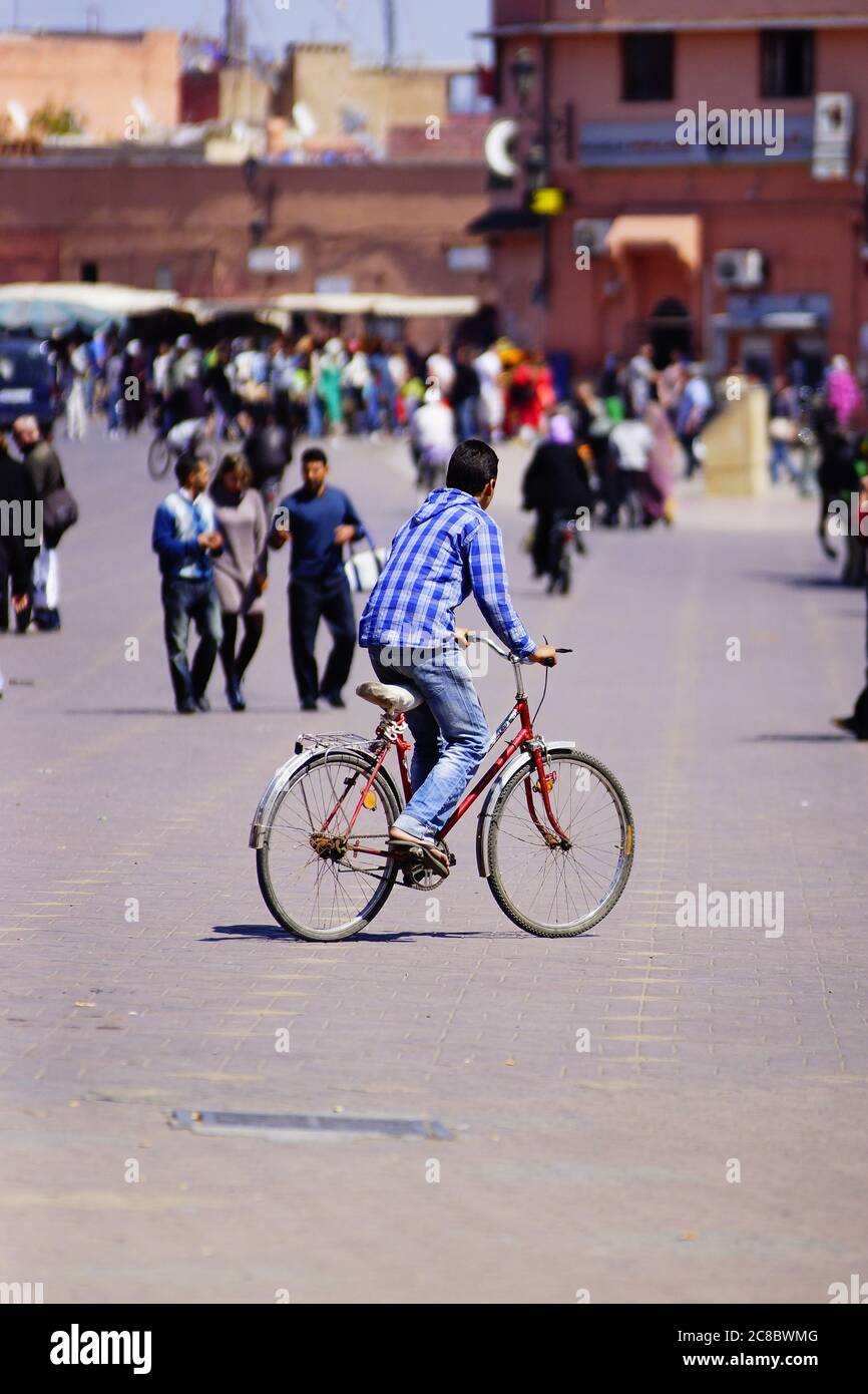 Uomo che guida una bicicletta attraverso la città di Marrakech Foto Stock