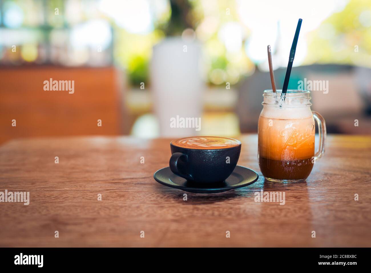 Bicchieri di latte art ghiacciato su tavolo di legno. Luce naturale, atmosfera rilassante del mattino, caffè, luce solare offuscata, natura Foto Stock