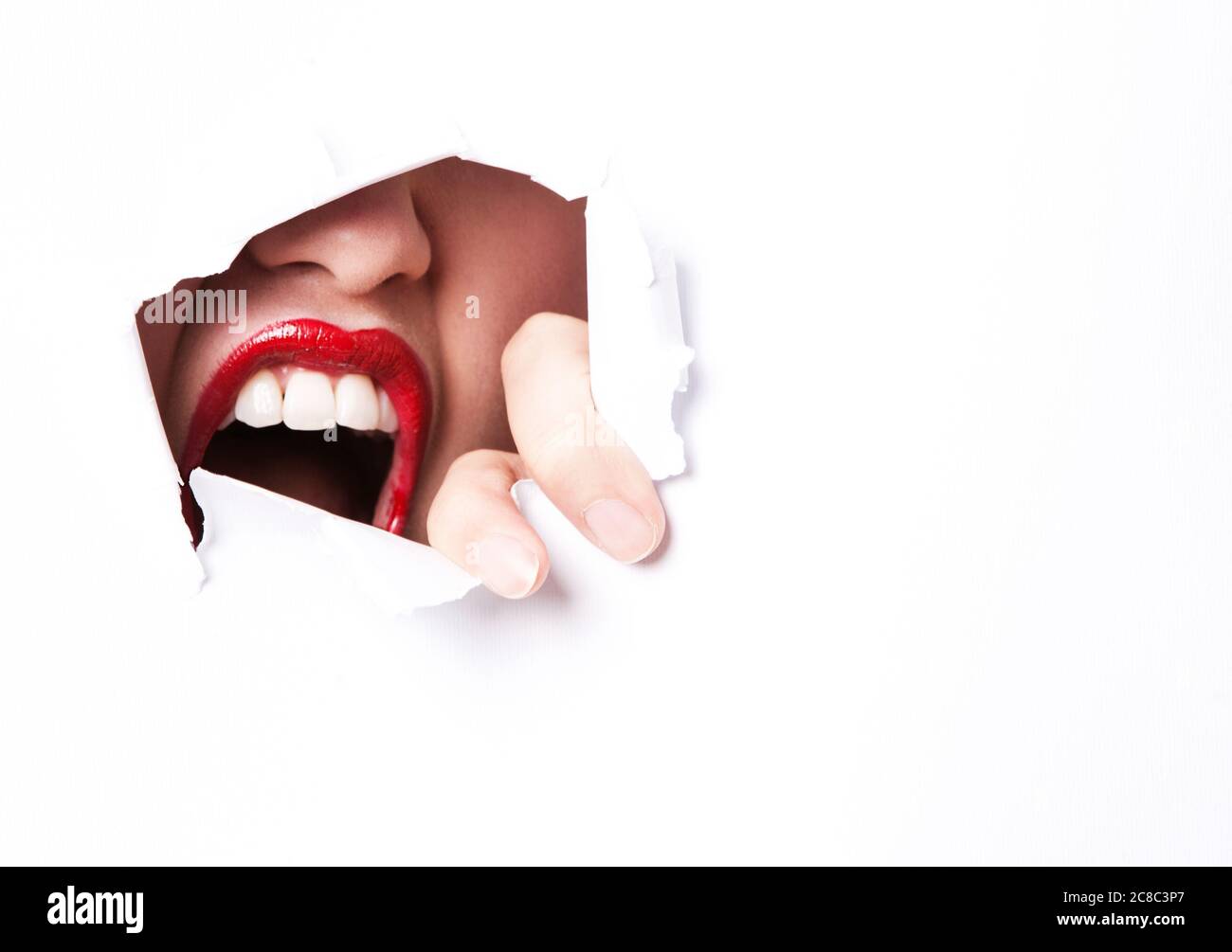Labbra rosse e bocca che sbucciano attraverso la carta strappata Foto Stock