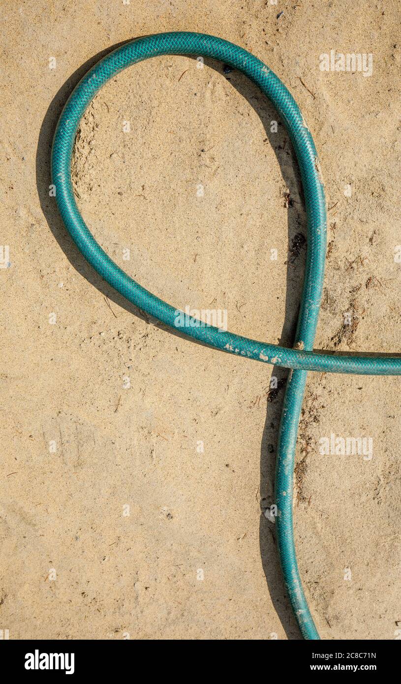 Tubo dell'acqua verde che si posa a terra e forma un anello Foto Stock