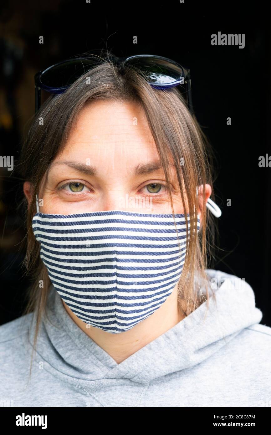 Primo piano ritratto di persona bella donna che indossa gli occhi sorridenti sotto il facemask durante la pandemia covid in estate luglio 2020 Gran Bretagna. KATHY DEWITT Foto Stock