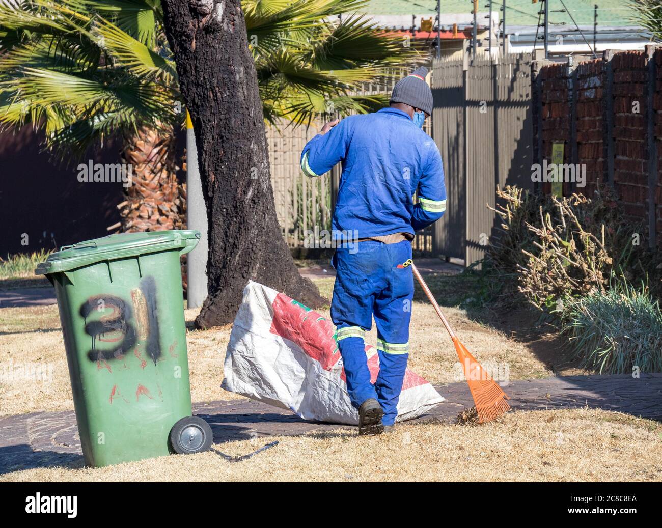 Alberton, Sudafrica - uomini neri non identificati lavorano come operai informali che fanno il lavoro di servizio del giardino in un giardino residenziale Foto Stock