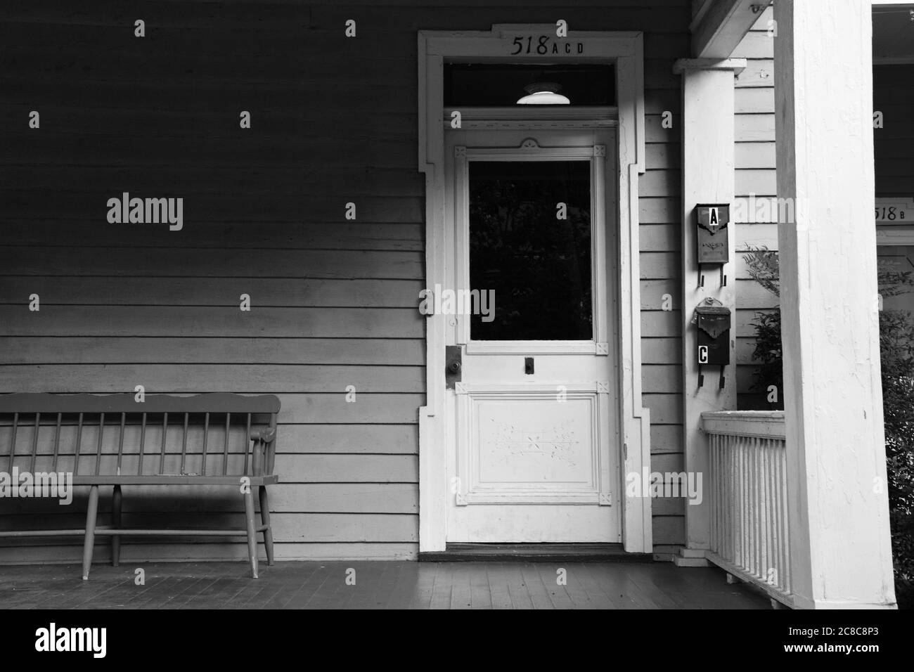 Fotografia in bianco e nero della porta e panca del portico anteriore di una casa storica a Raleigh, Carolina del Nord. Foto Stock
