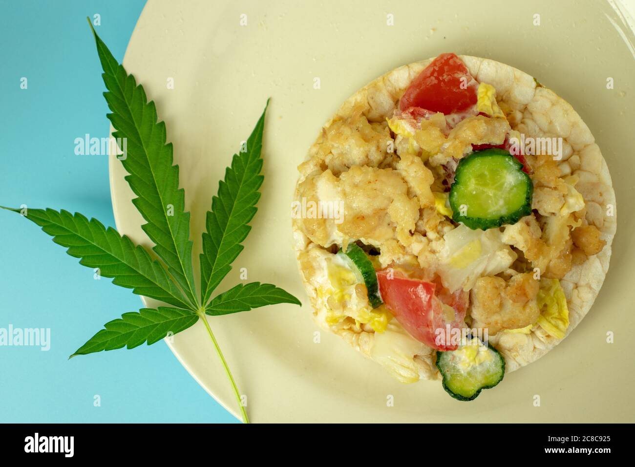 Cannabis Marijuana foglia verde su piatto con cibo sano vista dall'alto. Sfondo blu. Weed biologico Foto Stock