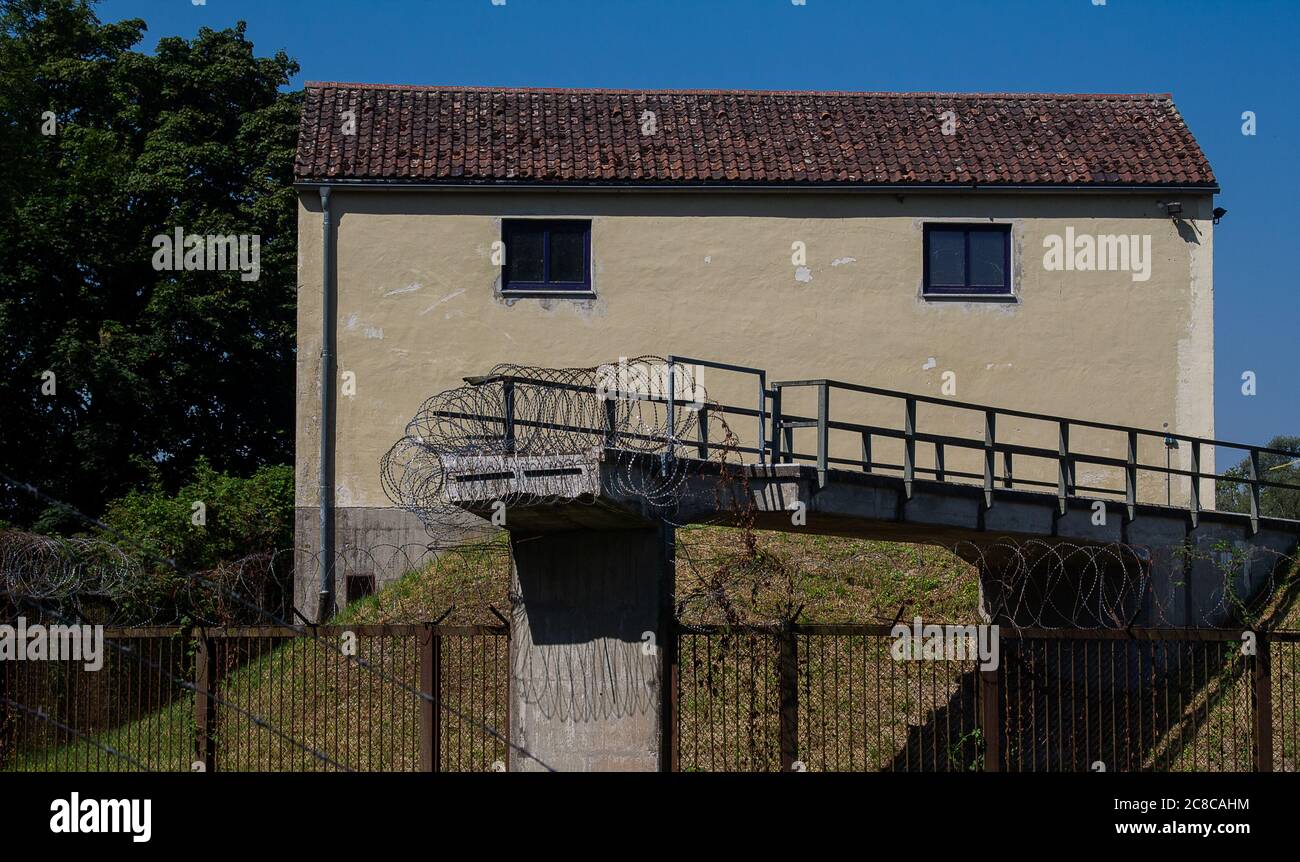 Un ponte di taglio fissato saldamente con filo dentellato contro l'ingresso. Sullo sfondo una vecchia casa. Foto Stock