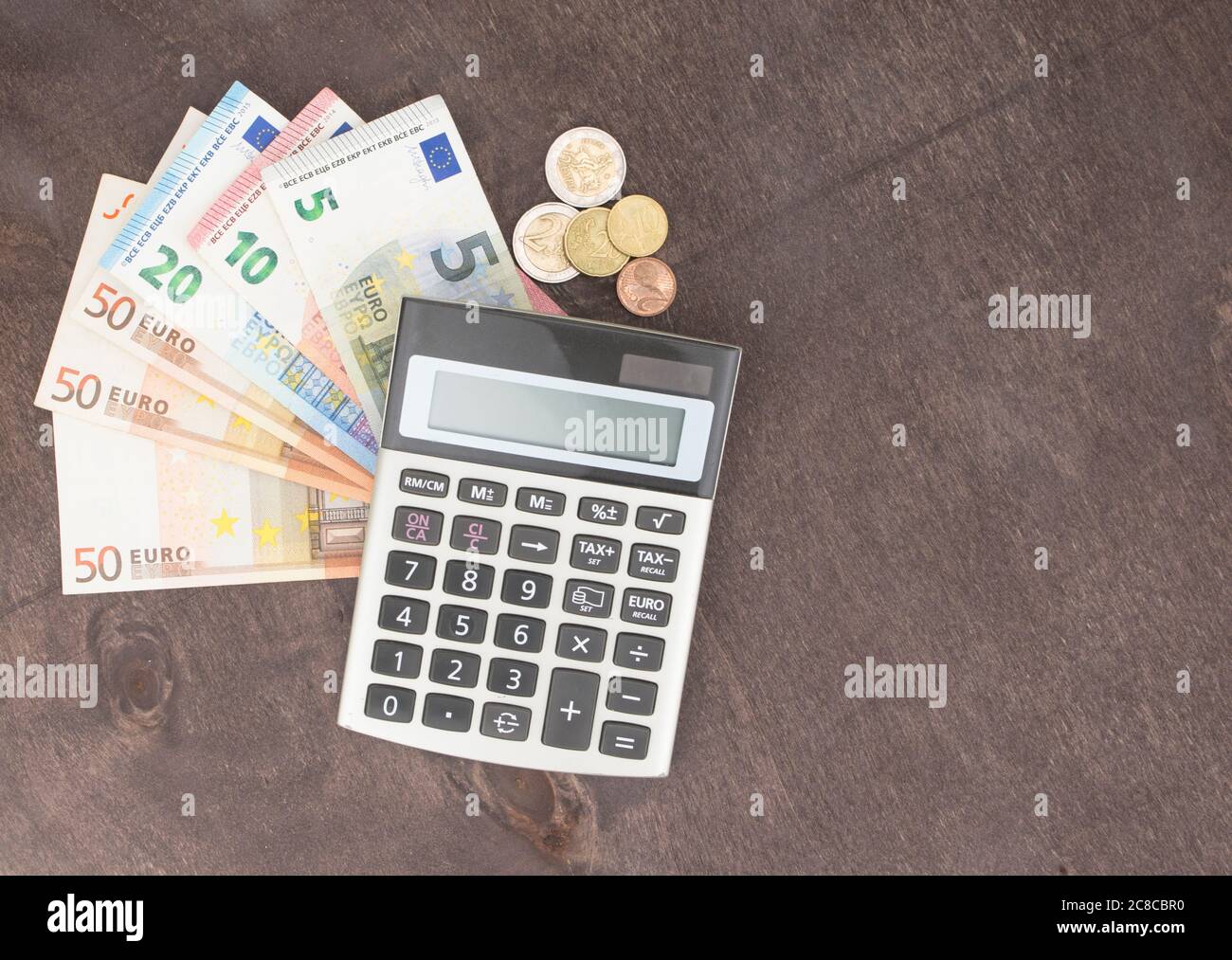 Le banconote e le monete in euro con la calcolatrice. Le banconote in euro su sfondo di legno. Foto per tassa, il profitto e la determinazione dei costi. 50 euro, 20 euro, 10 euro. Denaro e fina Foto Stock