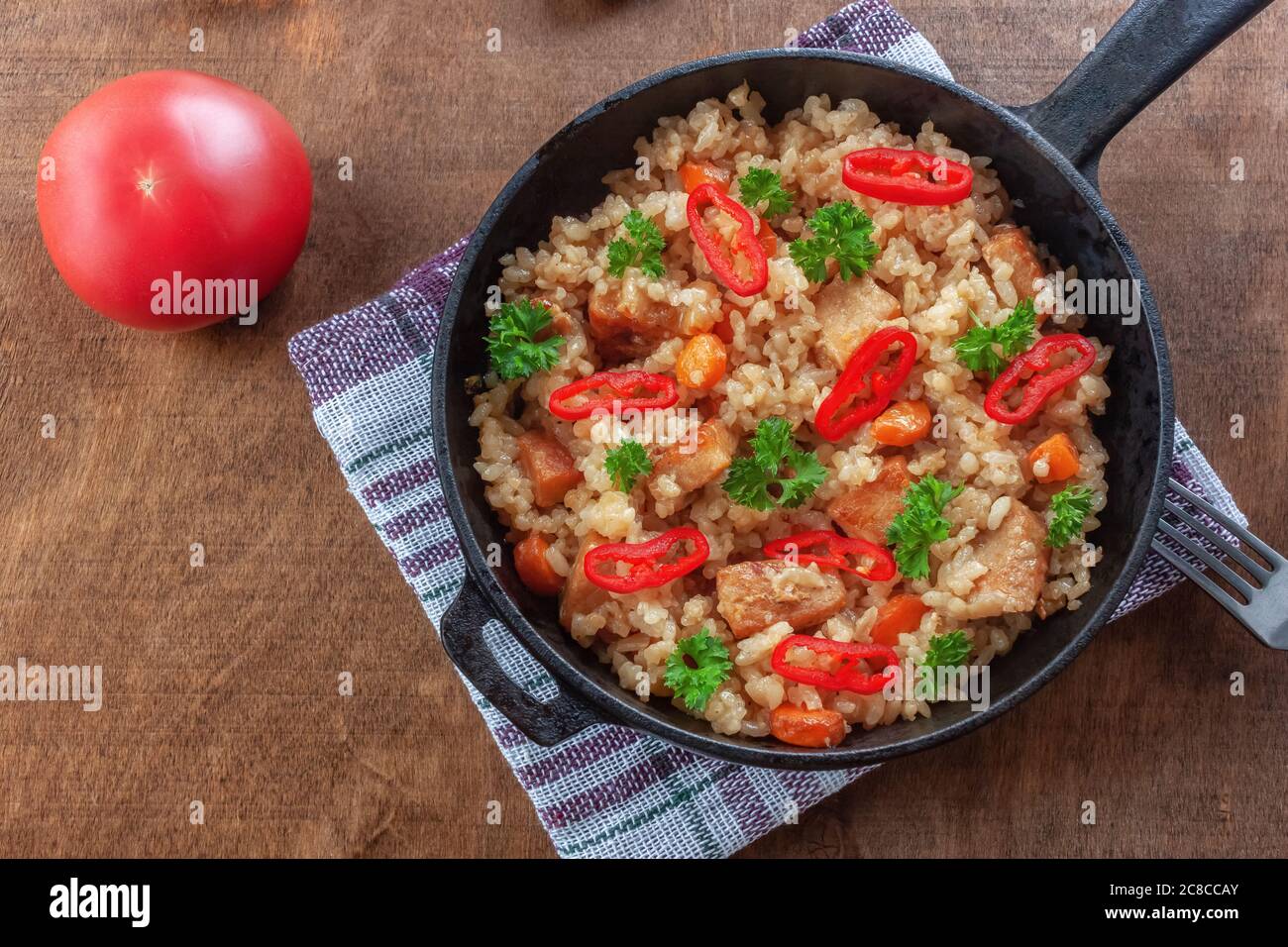 Riso con carne, verdure e prezzemolo in una padella Foto Stock