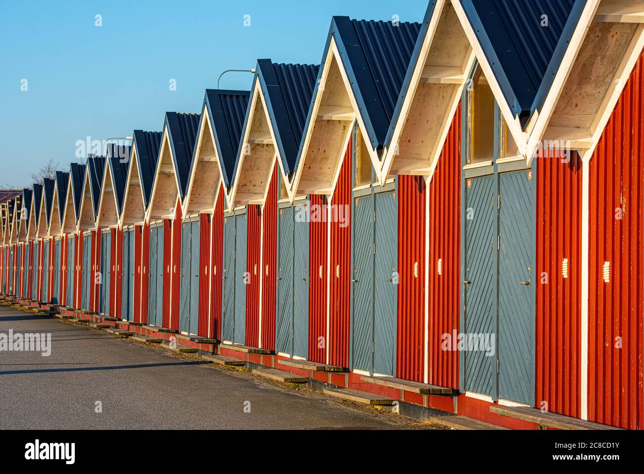 Lunga fila di piccole case di stoccaggio rosse con porte blu. Foto Stock