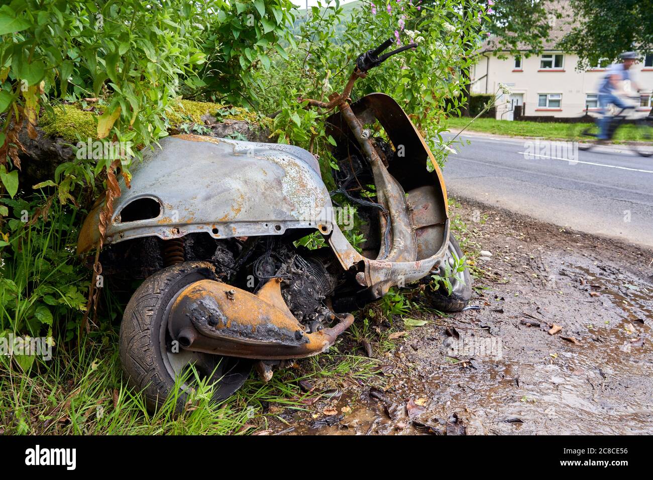 Un ciclomotore bruciato abbandonato a lato di una strada, Cardiff, Galles del Sud Foto Stock