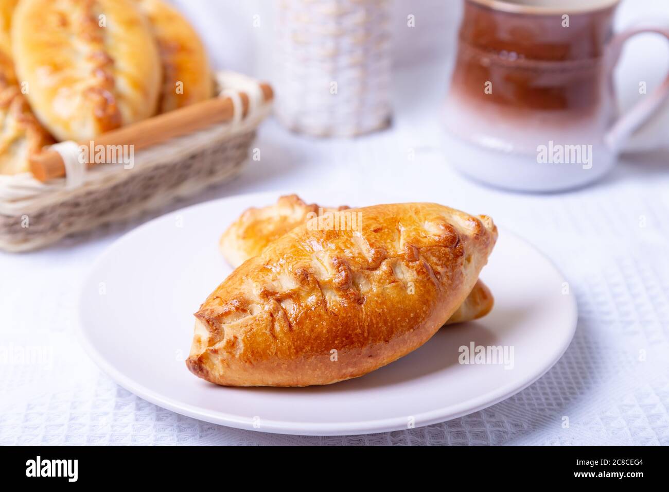 Pies (pirozhki) con cavolo. Cottura fatta in casa. Cucina tradizionale russa e Ucraina. Sullo sfondo c'è un cestino con torte. Primo piano. Foto Stock