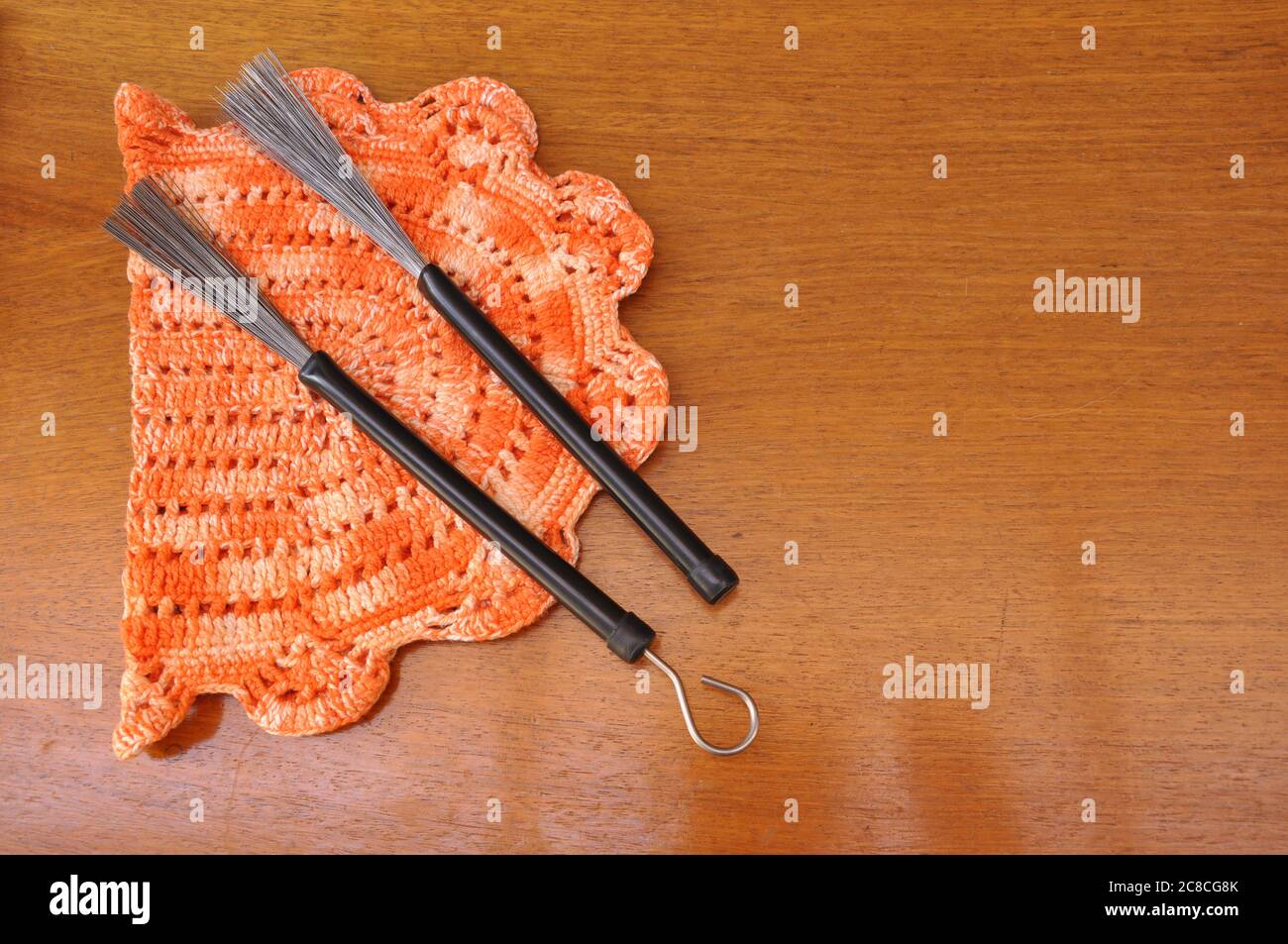 Bastoni in metallo a tamburo, utilizzati in jazz sulla cima di una tovaglia di pizzo con dettagli arancioni su sfondo di legno, vista dall'alto verso il basso Foto Stock