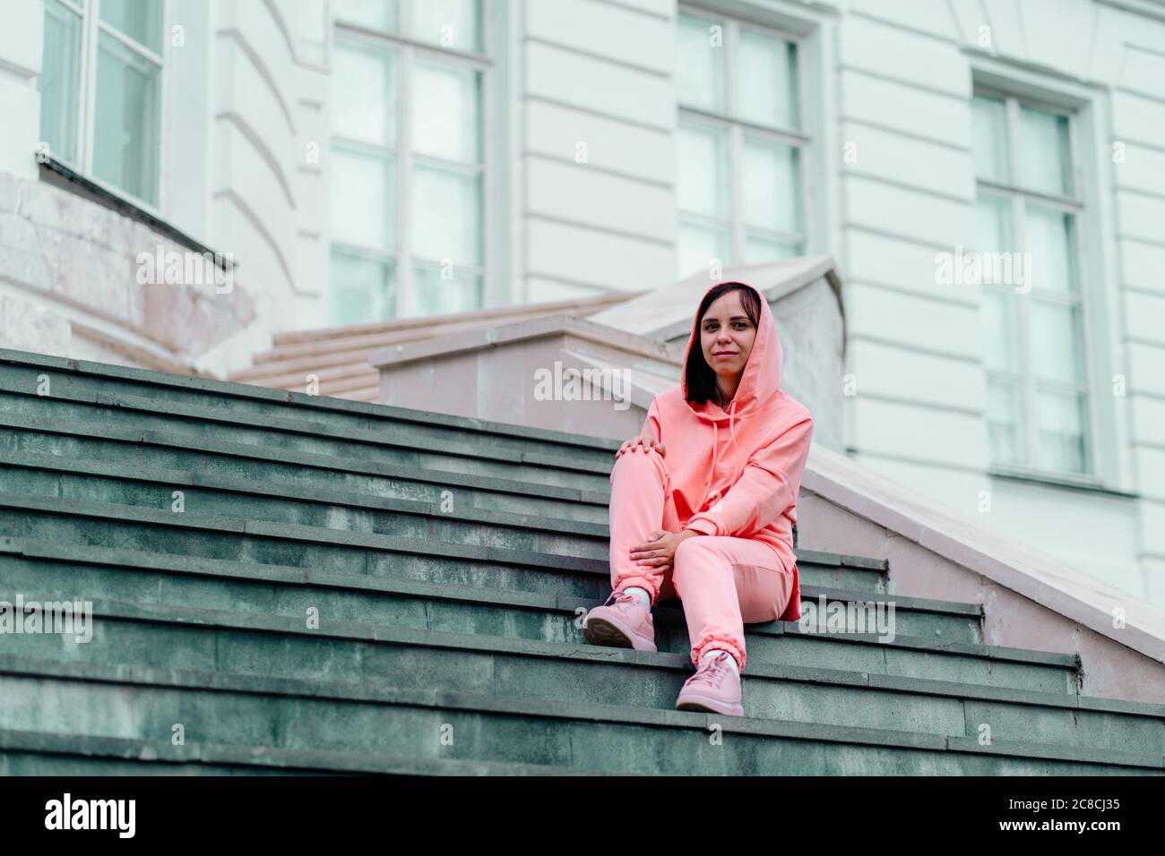 Giovane donna posa su scale di maniero. Donna adulta seduta sui gradini del palazzo. Foto Stock