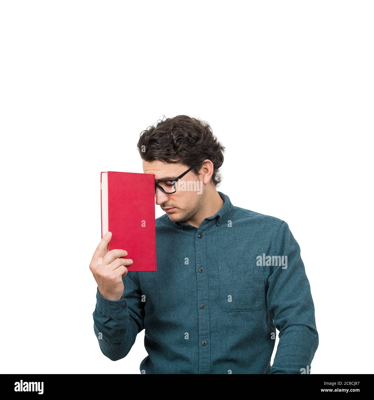 Stanco studente ragazzo guardando giù con pessimismo emozione, tenendo un libro, isolato su sfondo bianco. Il giovane confuso ha problemi di apprendimento, probl Foto Stock