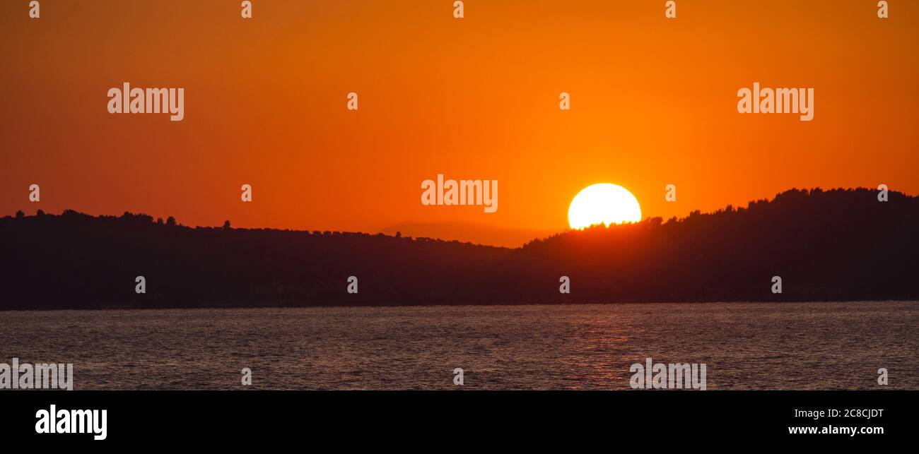 Sole che si affaccia sulle colline e sul mare Foto Stock