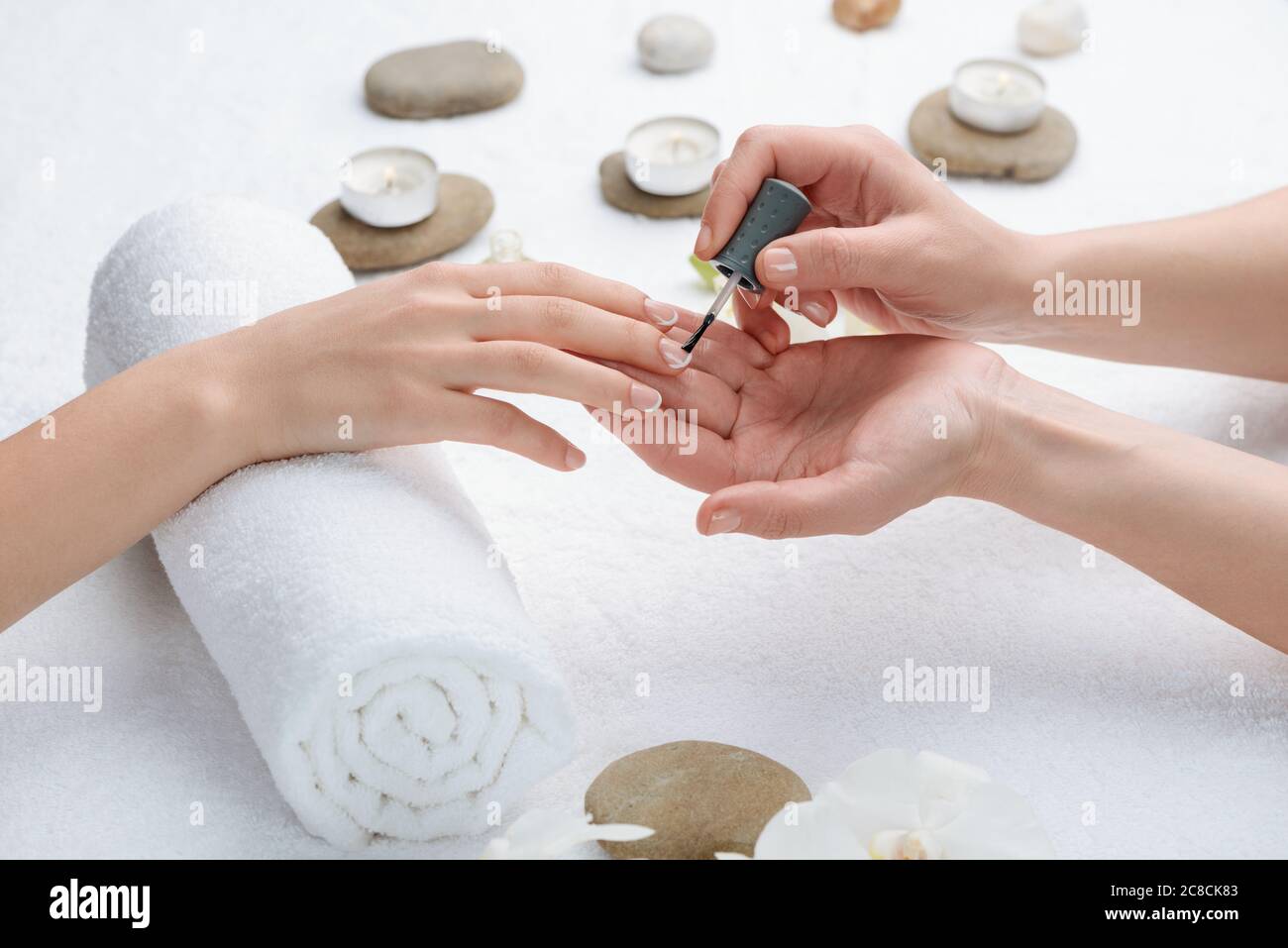 Manicure applicando il rivestimento di base. Fondazione trasparente per proteggere le unghie Foto Stock