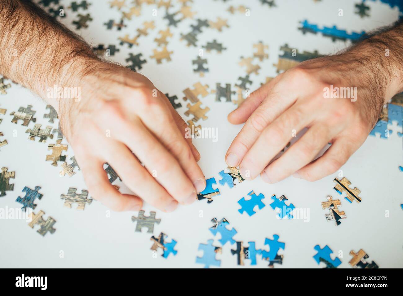 Mani che ordinano attraverso i pezzi del puzzle in cerca della soluzione necessaria al puzzle grafico Foto Stock