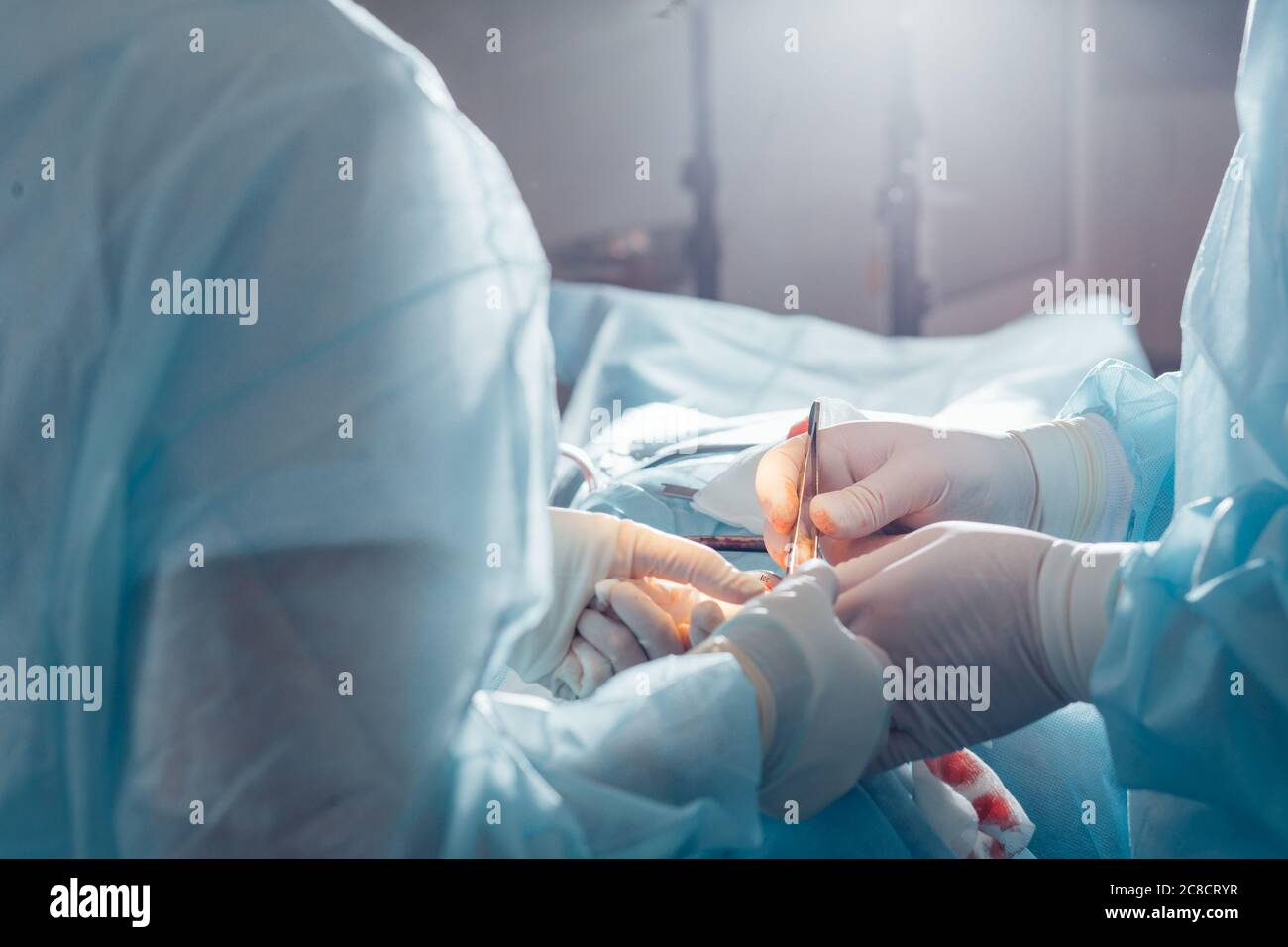 Primo piano del chirurgo e del suo assistente che esegue la chirurgia estetica in sala operatoria dell'ospedale. Medico che tiene gli strumenti chirurgici durante il medico Foto Stock