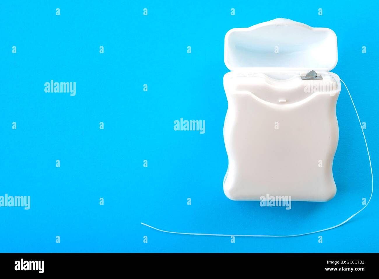 Concetto di igiene dentale e salute orale con scatola per filo interdentale isolata su sfondo blu con spazio per la copia Foto Stock