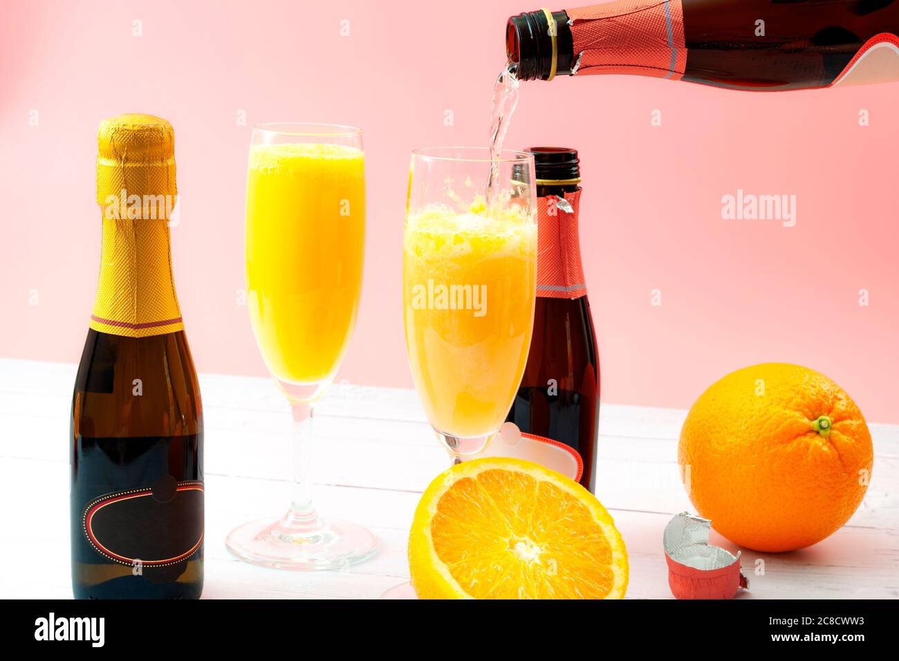 Bevande miste, bevande alcoliche estive e cocktail mimosa per il brunch rinfrescante con frutta d'arancia e champagne da una bottiglia di bu Foto Stock
