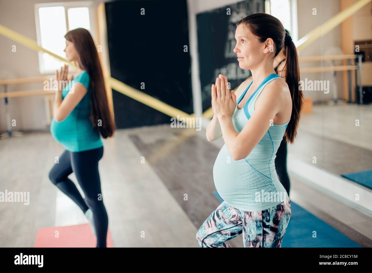 Donne incinte giovani in albero posano yoga posizione in sala fitness Foto Stock
