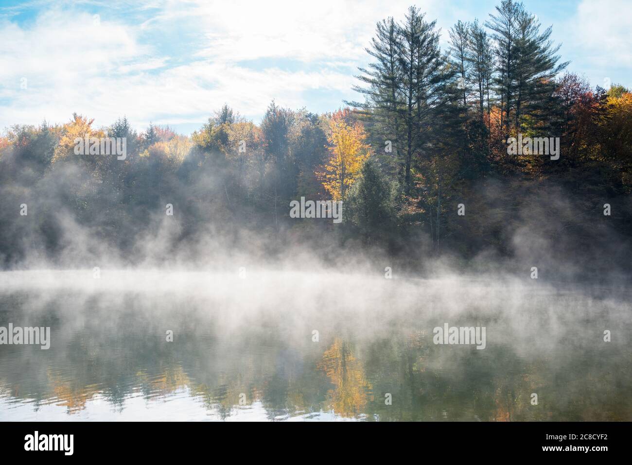 Lago di montagna coperto in nebbia mattutina in autunno Foto Stock