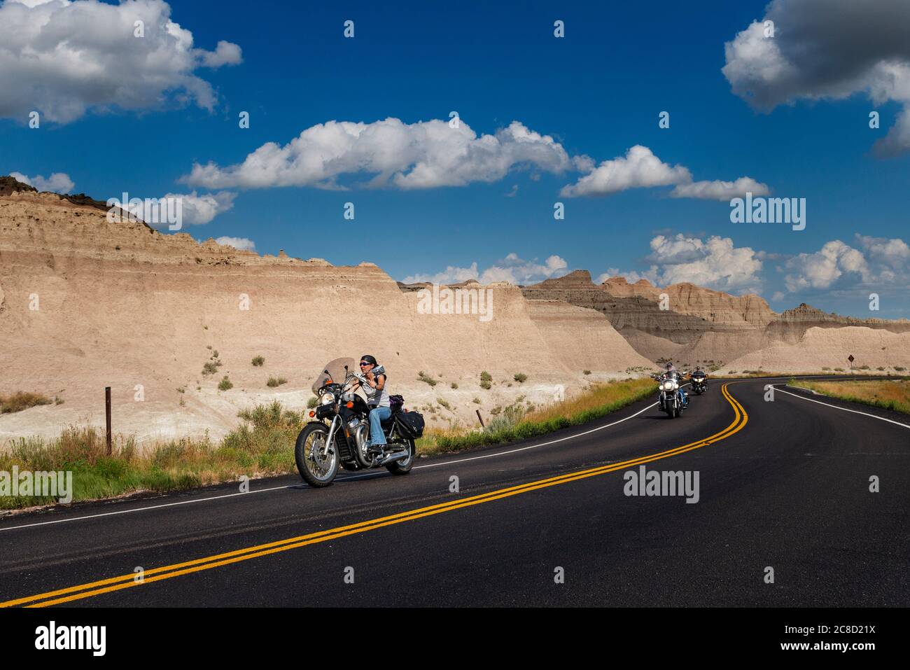 Badlands National Park, South Dakota - 9 agosto 2014: Motociclisti che cavalcano le loro moto chopper su una strada sterrata al Badlands National Park. Foto Stock