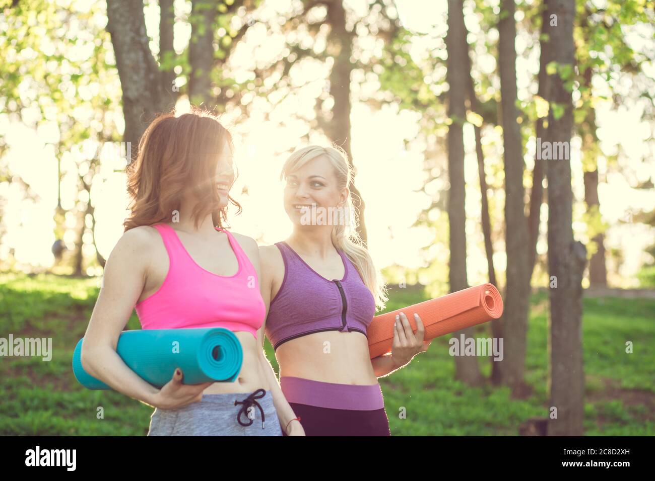 Due Fitness Girl con tappetino yoga in piedi Outdoor in natura - Fit donna con accessorio per l'esercizio in estate paesaggio Foto Stock