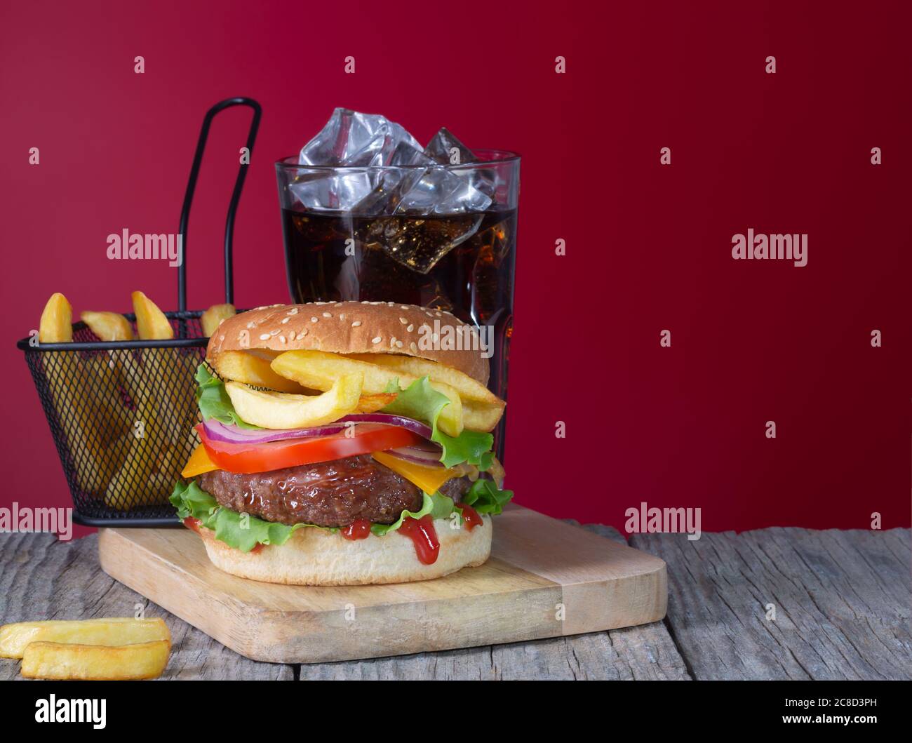 Hamburger di manzo fresco e succoso con patatine fritte e cola su sfondo di legno con spazio per la copia Foto Stock
