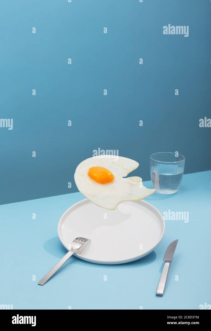 Uova fritte volanti su sfondo blu, stile creativo isometrico, orientamento verticale Foto Stock