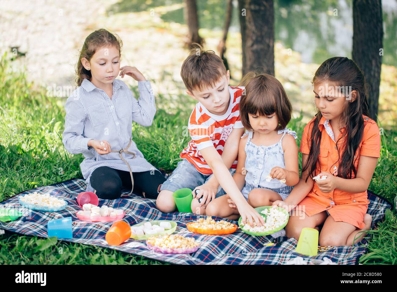 I bambini mangiano il pranzo all'aperto. Bambini con cestino da picnic nel  giardino primaverile Foto stock - Alamy
