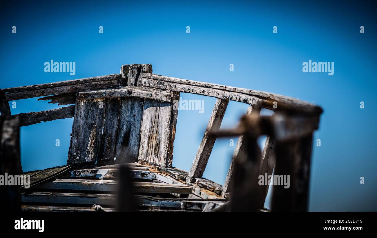 Derelict abbandonato barca da pesca in legno, legno gnarly e vernice flaking su ciottoli Dungeness Shale spiaggia Foto Stock