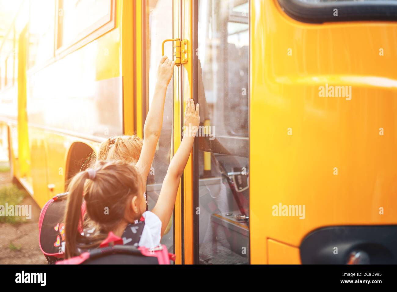 Le studentesse con gli zaini entrano nel bus scolastico, tornano a scuola Foto Stock