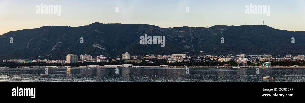 Panorama molto ampio e vista serale della città di Gelendzhik, molti edifici ai piedi delle maestose montagne, un bellissimo paesaggio estivo Foto Stock