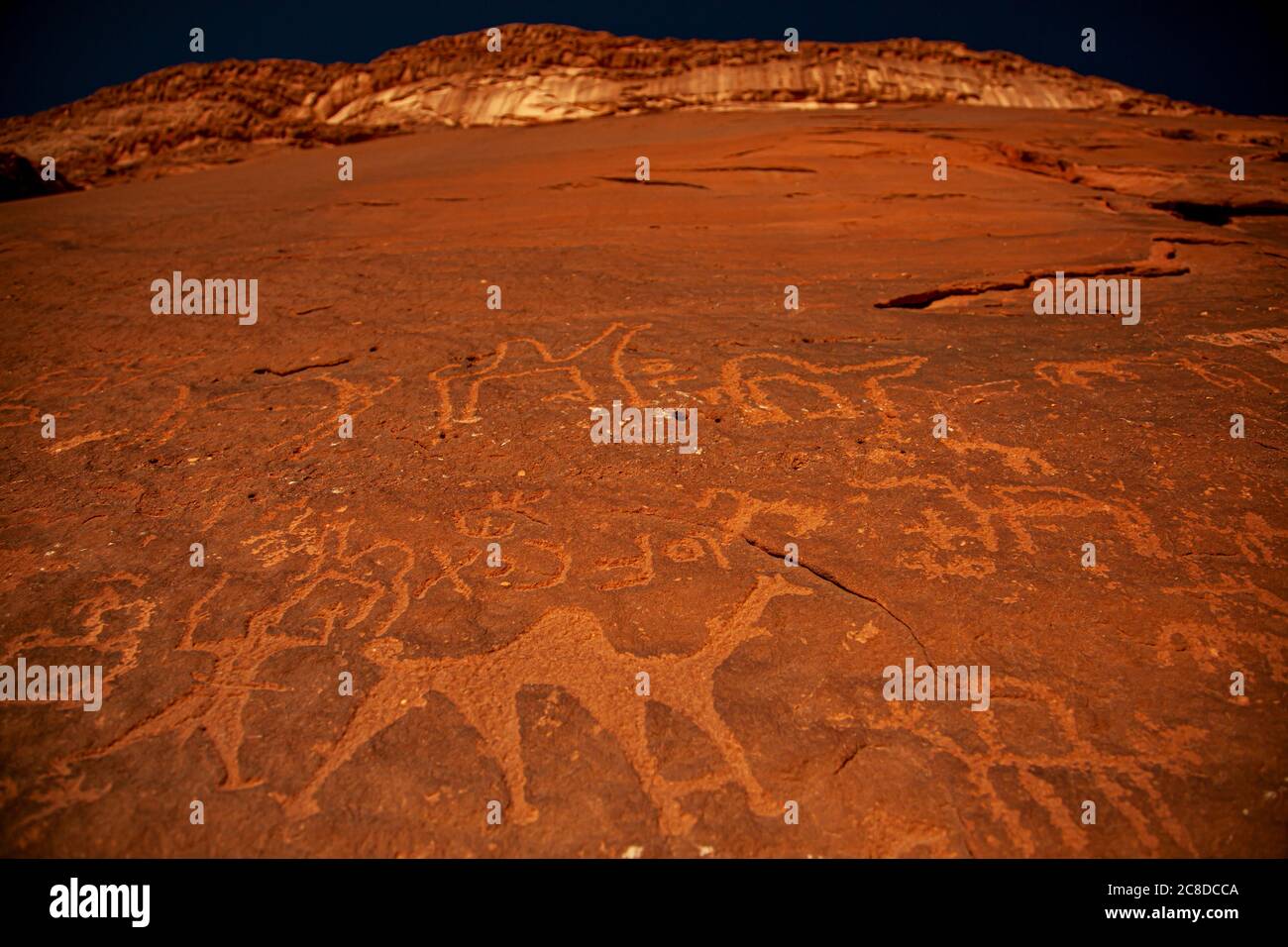 Primo piano con le iscrizioni preistoriche in pietra e i petroglifi fatti dai beduini nomadi sulla superficie delle rocce di arenaria rossa di Wadi Rum Jordan. Foto Stock
