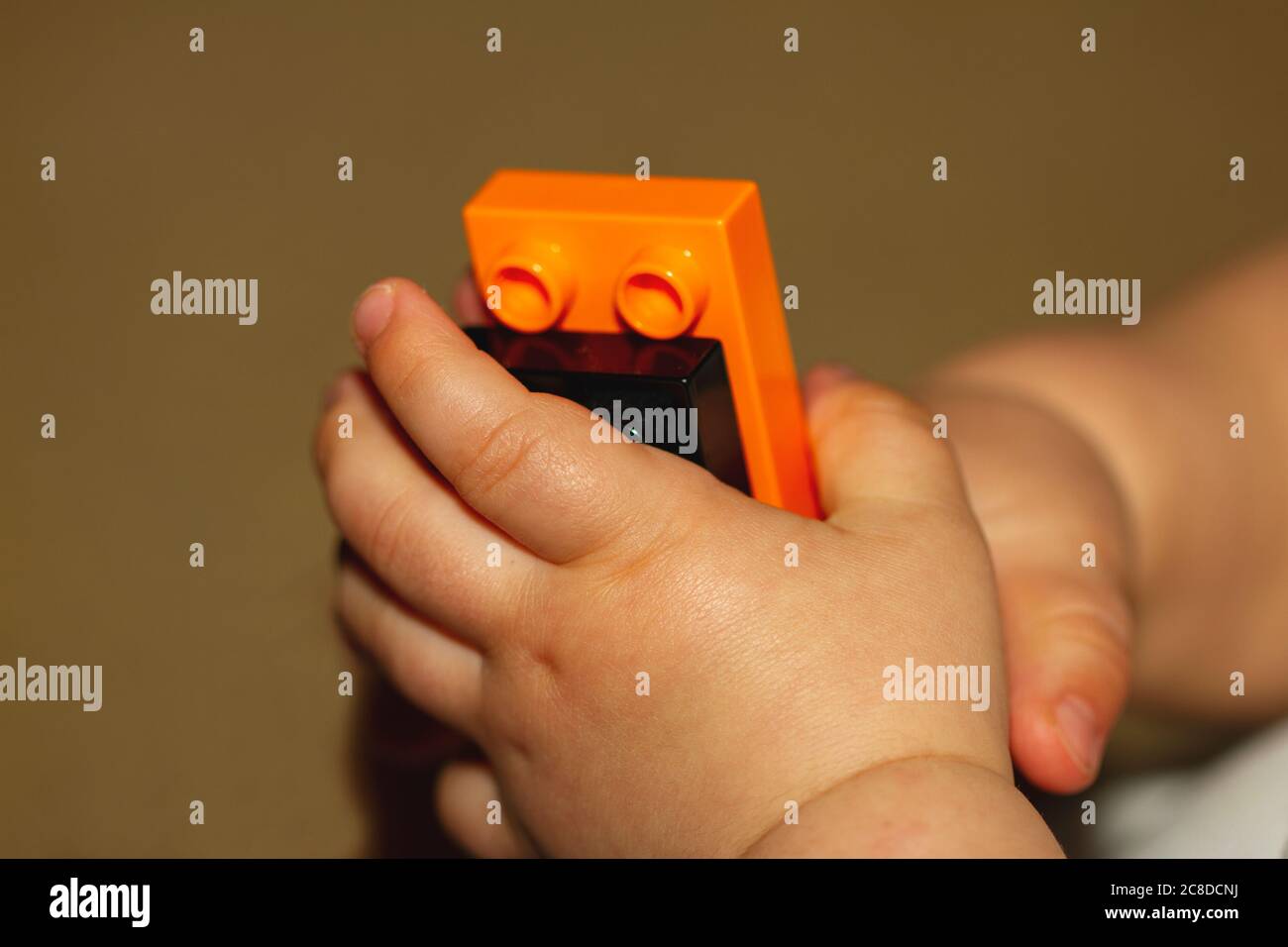 Immagine ravvicinata delle mani di un bambino che sta cercando di mettere insieme dei blocchi. L'immagine è utile per dimostrare lo sviluppo di motori, motori di precisione Foto Stock