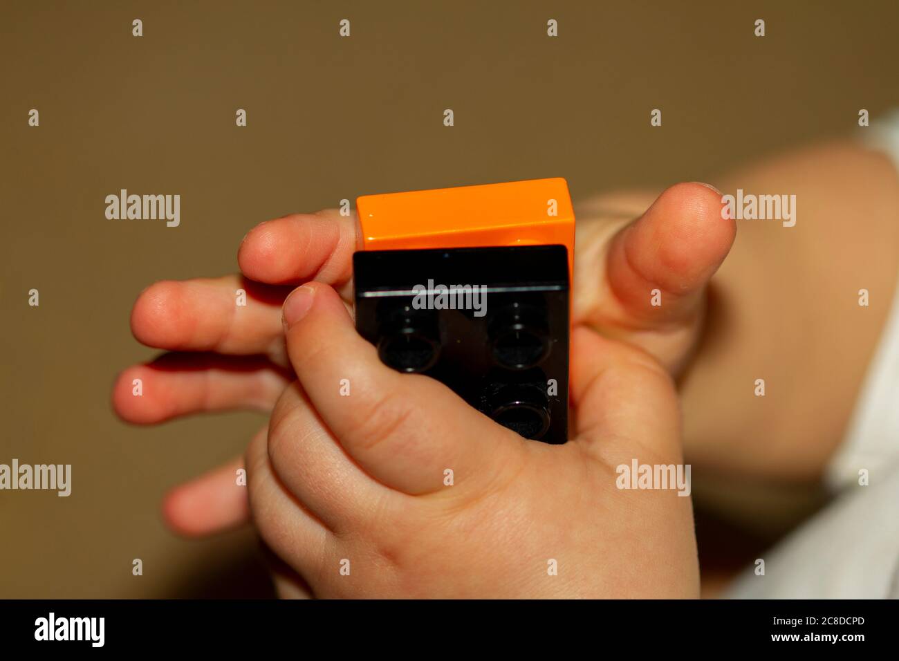 Immagine ravvicinata delle mani di un bambino mentre sta cercando di bloccare due mattoncini giocattolo. L'immagine è utile per dimostrare lo sviluppo del motore, la fine del motion Foto Stock