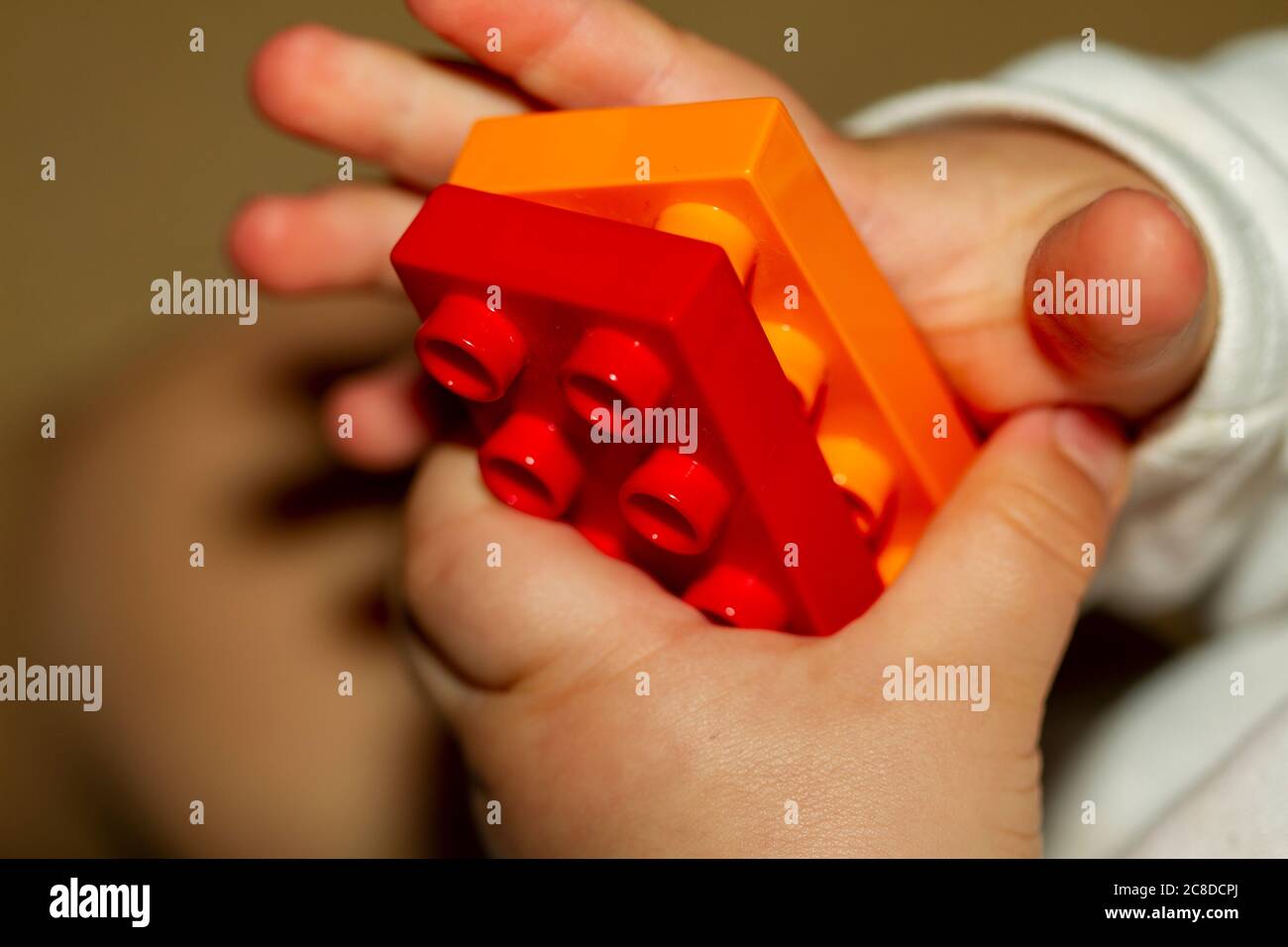 Immagine ravvicinata delle mani di un bambino mentre sta cercando di bloccare due mattoncini giocattolo. L'immagine è utile per dimostrare lo sviluppo del motore, la fine del motion Foto Stock