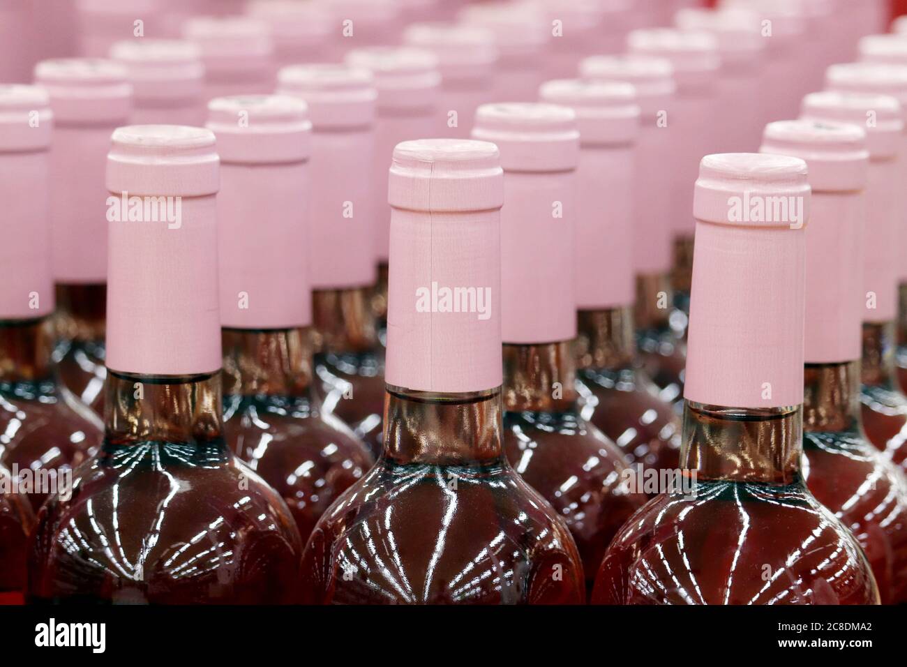 Bottiglie di vino in fila, fuoco selettivo. Negozio di liquori, concetto di produzione di vino rosa Foto Stock