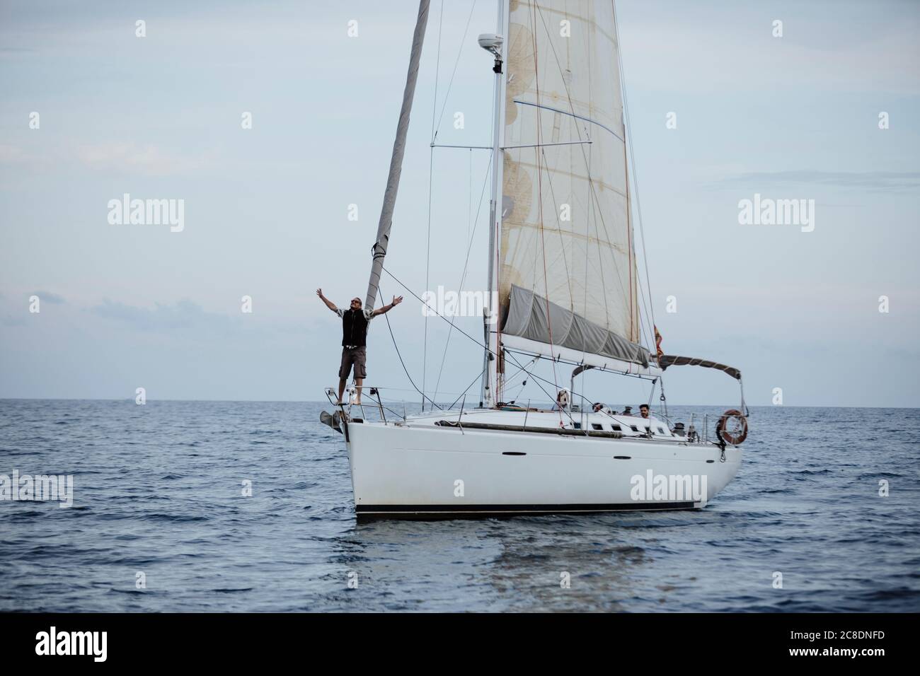 Marinaio femminile con le braccia sollevate in piedi sulla barca a vela in mare Foto Stock