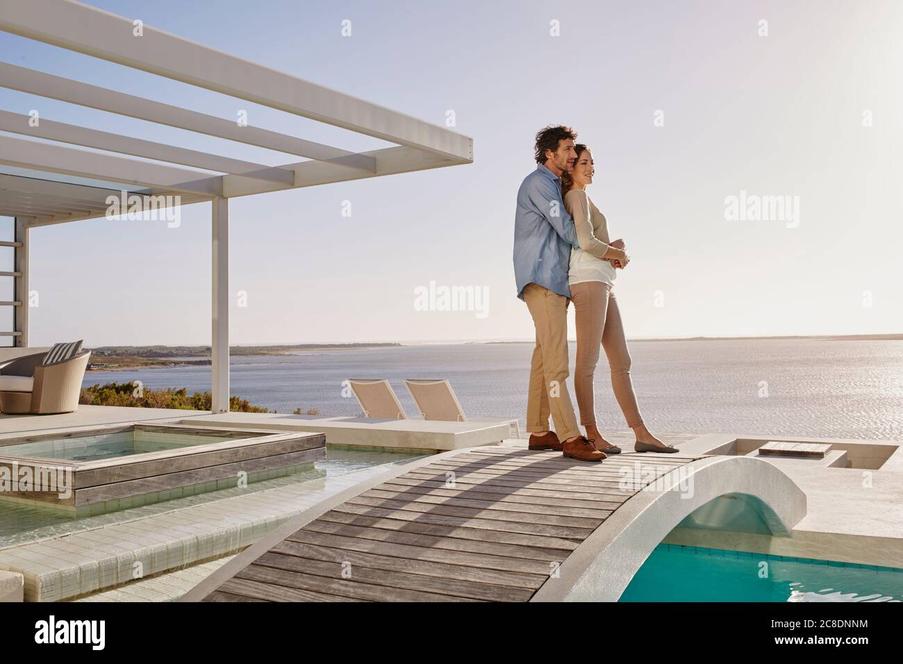 Affettuosa coppia che si erge sul ponte sopra una piscina godendo la vista Foto Stock