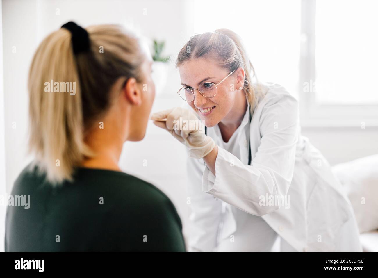 Medico femminile che esamina la paziente femminile con depressore della lingua Foto Stock