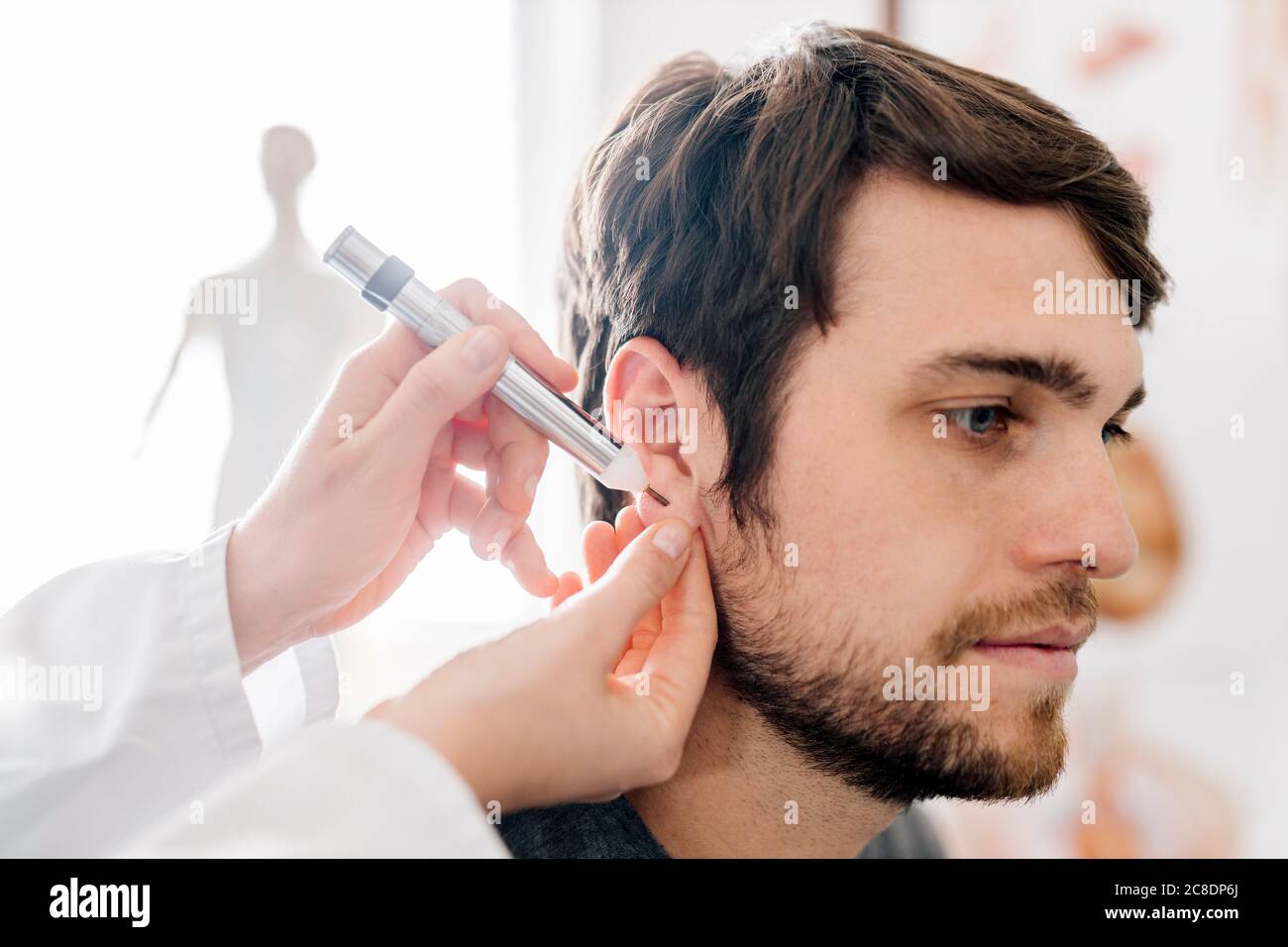 Praticante alternativo femminile che dà agopuntura dell'uomo con akupen nell'orecchio Foto Stock
