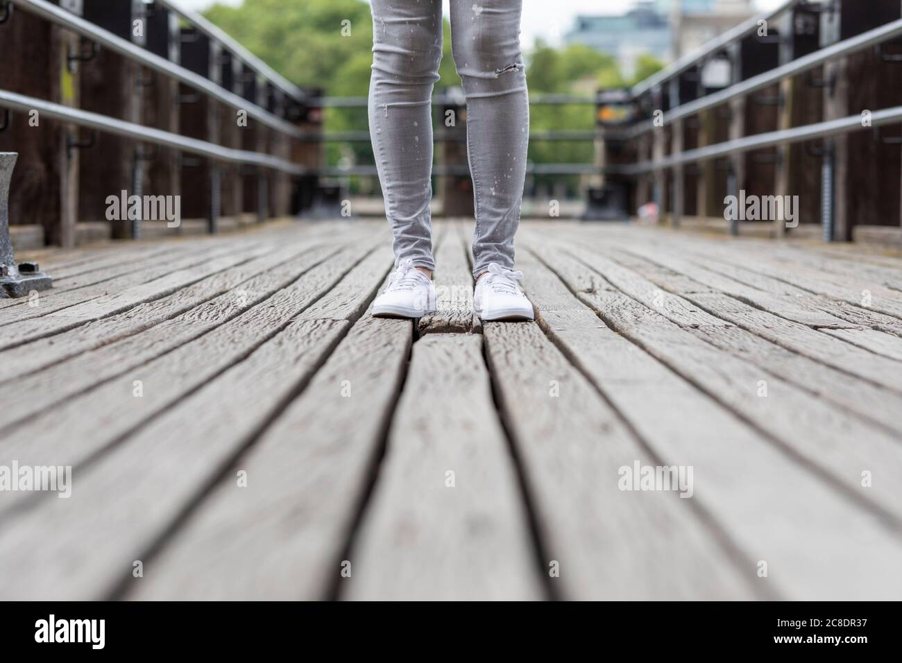 Primo piano di gambe donna in piedi sul ponte in città Foto Stock