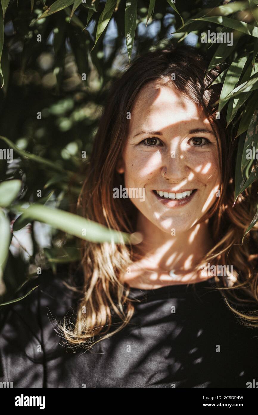 Primo piano di sorridente donna mid adulta da piante in cortile Foto Stock