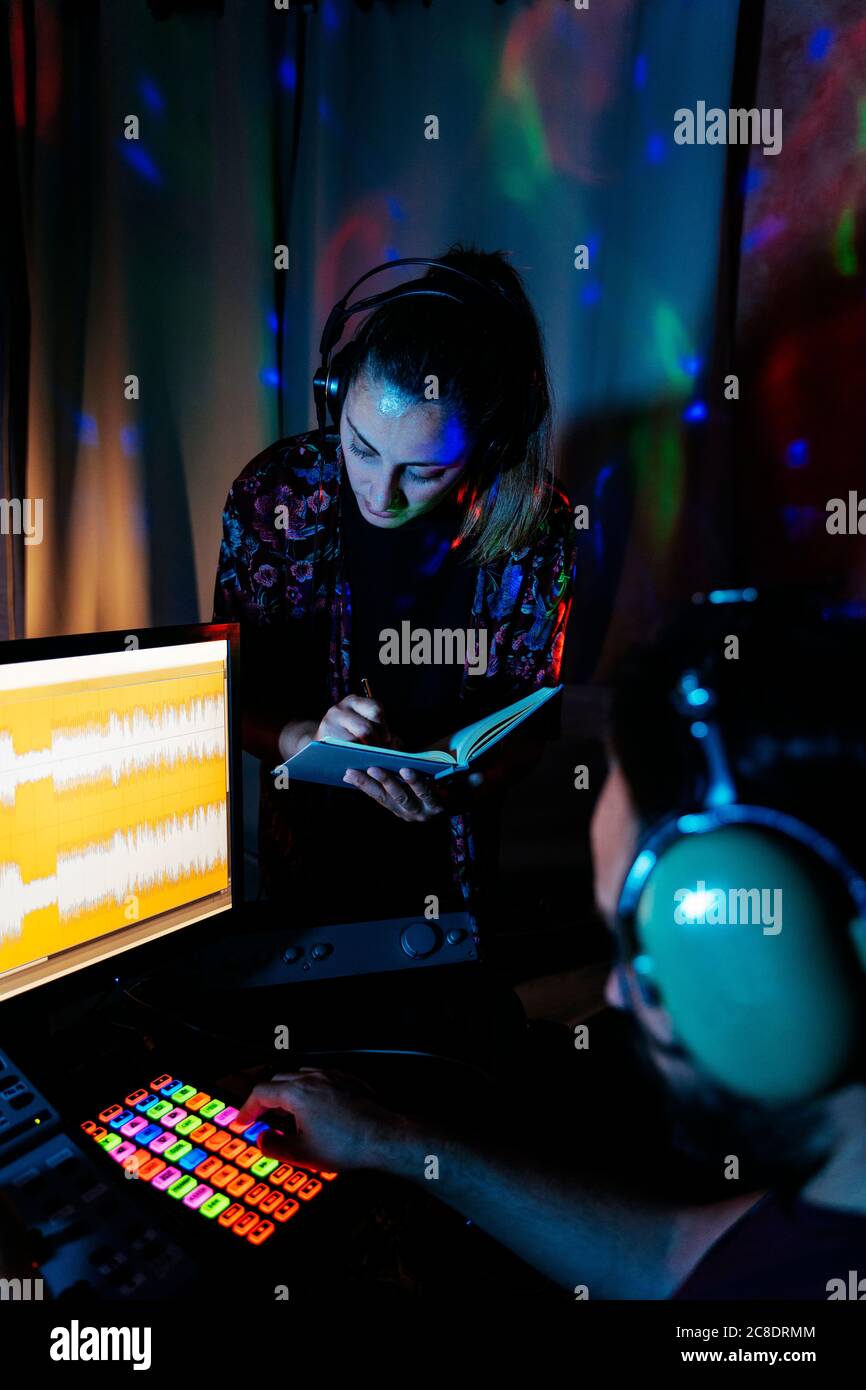 Coppia musicista che usa il computer in uno studio di registrazione illuminato a casa Foto Stock