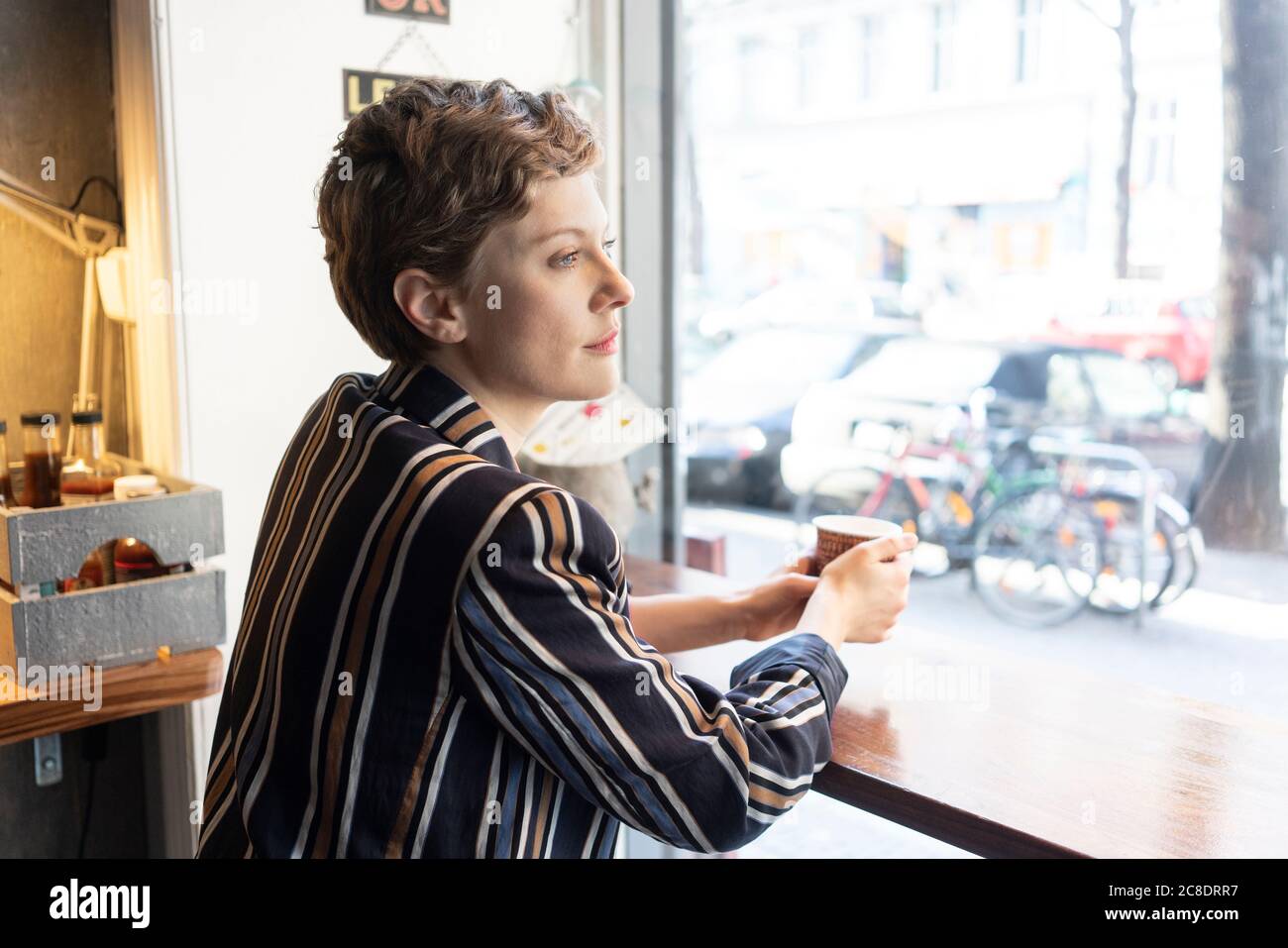 Un'affusiva freelance in una caffetteria che si affaccia fuori dalla finestra Foto Stock