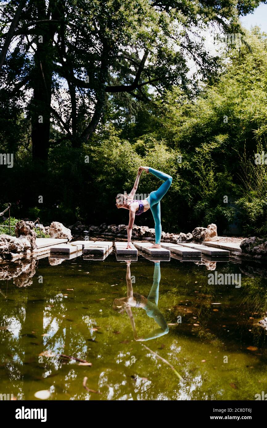 Donna consapevole della salute che fa yoga posa al parco pubblico Foto Stock