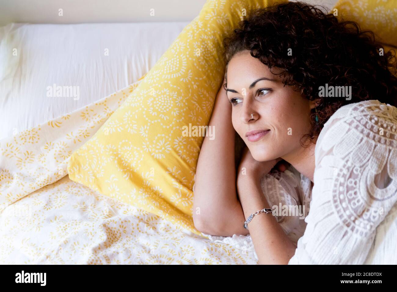 Donna giovane premurosa sdraiata sul letto in cottage Foto Stock