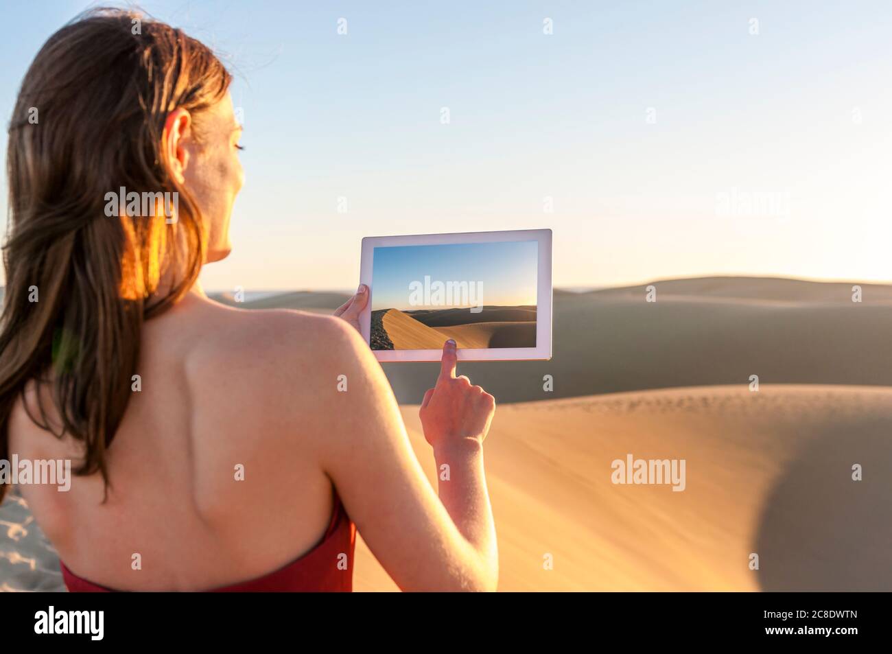 Donna che scattava una foto con un tablet al tramonto sulle dune, Gran Canaria, Spagna Foto Stock