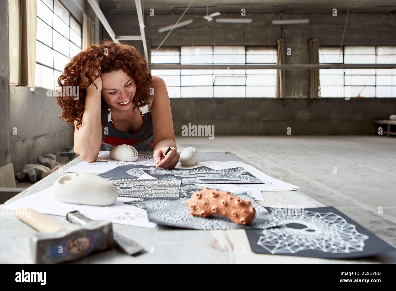 Stonemason femmina che disegna schizzi sul banco da lavoro in studio Foto Stock